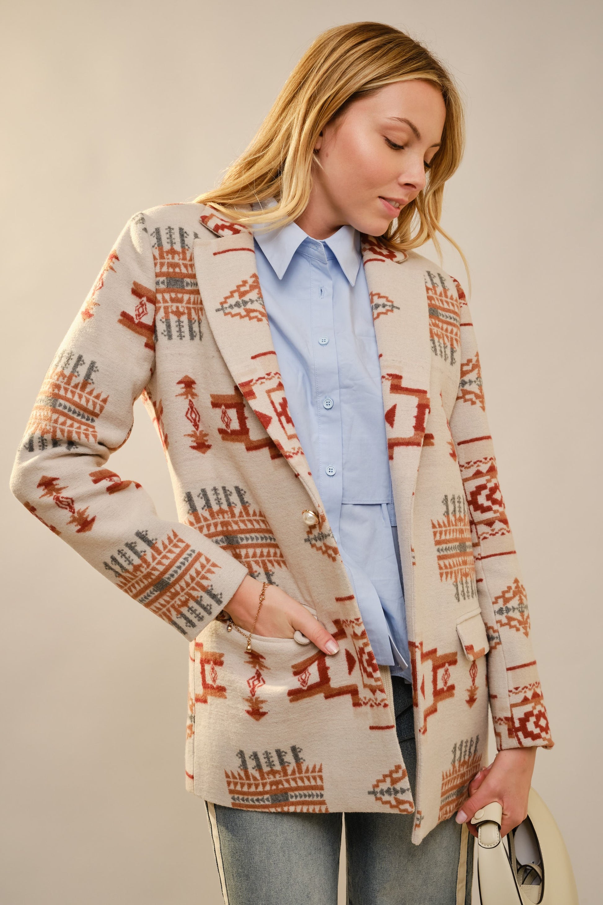 Woman wearing a patterned cardigan over a light blue shirt against a neutral background