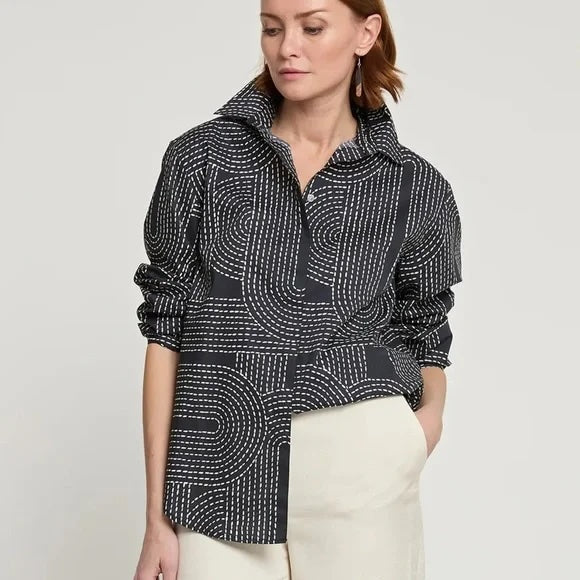 Woman wearing a black and white patterned jacket on a light gray background. Luxury for less